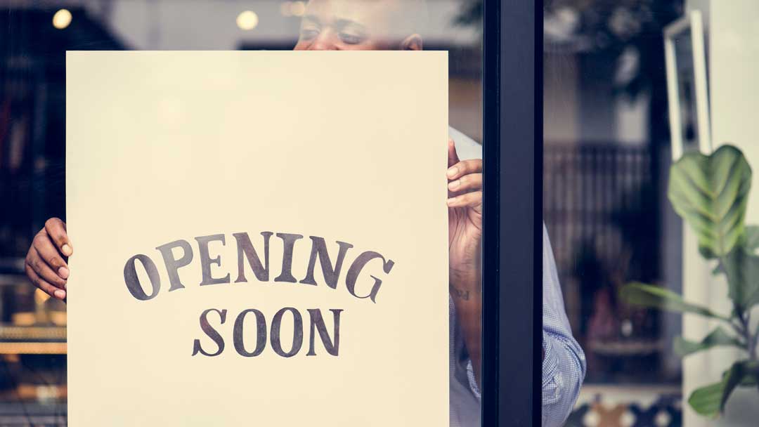 man putting store opening soon sign in window